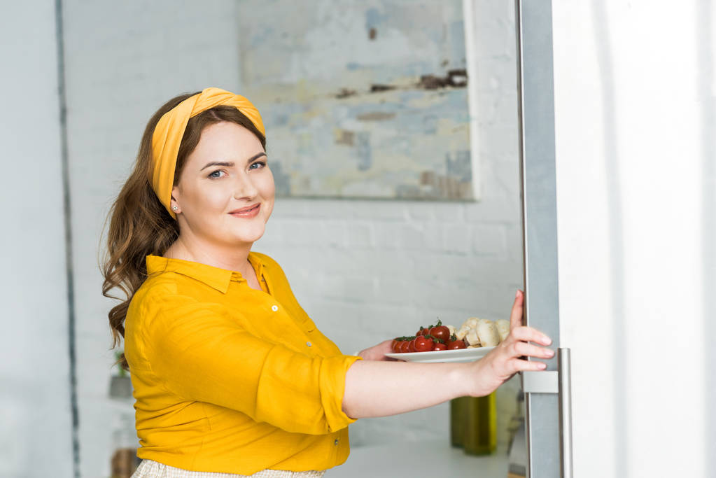 hermosa mujer sosteniendo plato con verduras en la cocina
 - Foto, Imagen