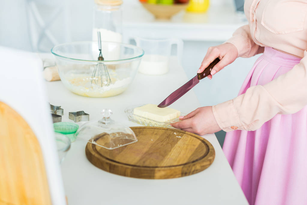 rajattu kuva nainen leikkaamalla voita keittiössä
 - Valokuva, kuva