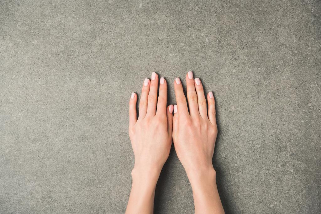 Oříznout záběr ženských rukou na šedém povrchu betonu - Fotografie, Obrázek