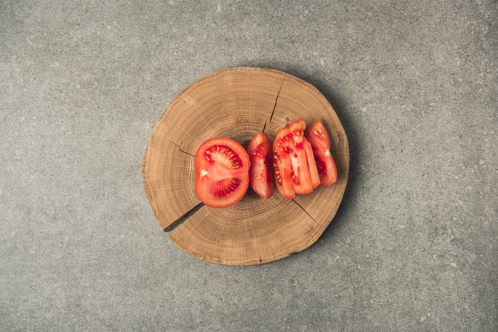 top view of cuted tomato on wooden stump on grey concrete tabletop - Photo, Image