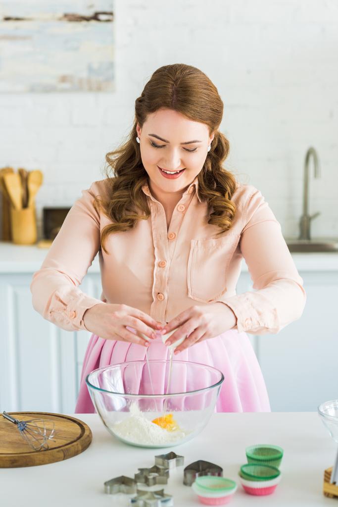kaunis nainen lisäämällä muna jauhoja taikina keittiössä
 - Valokuva, kuva