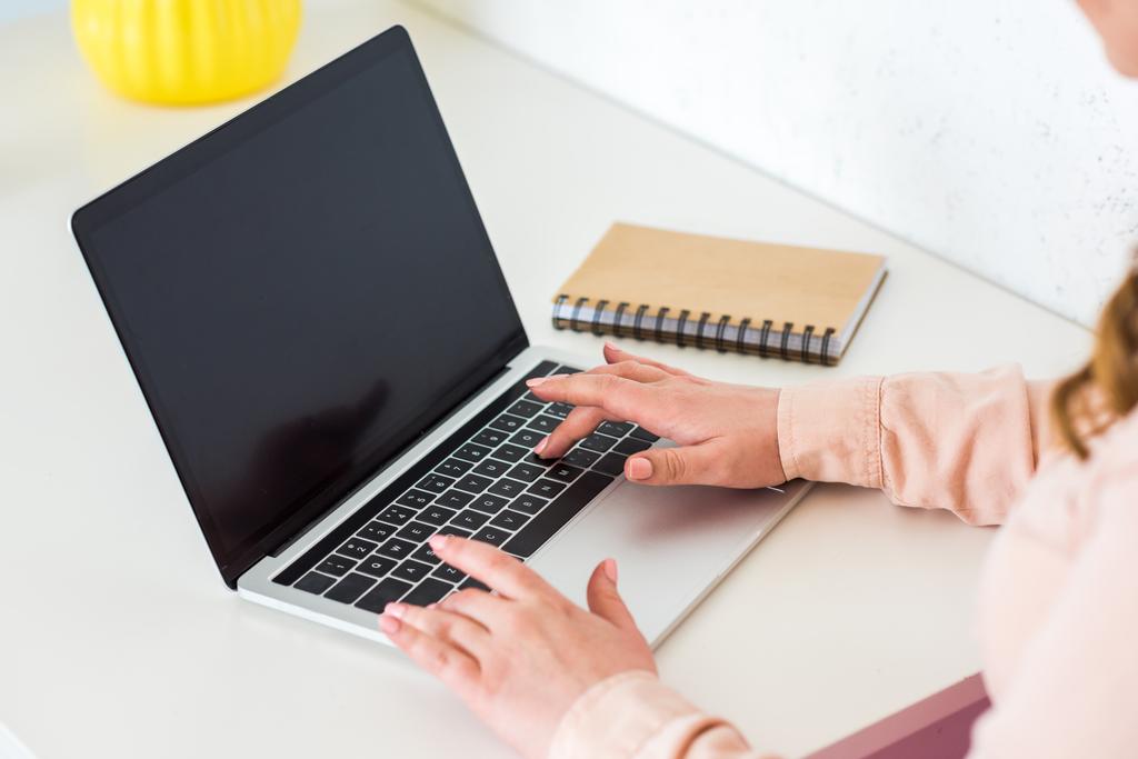 Immagine ritagliata di donna che utilizza il computer portatile a tavola
 - Foto, immagini