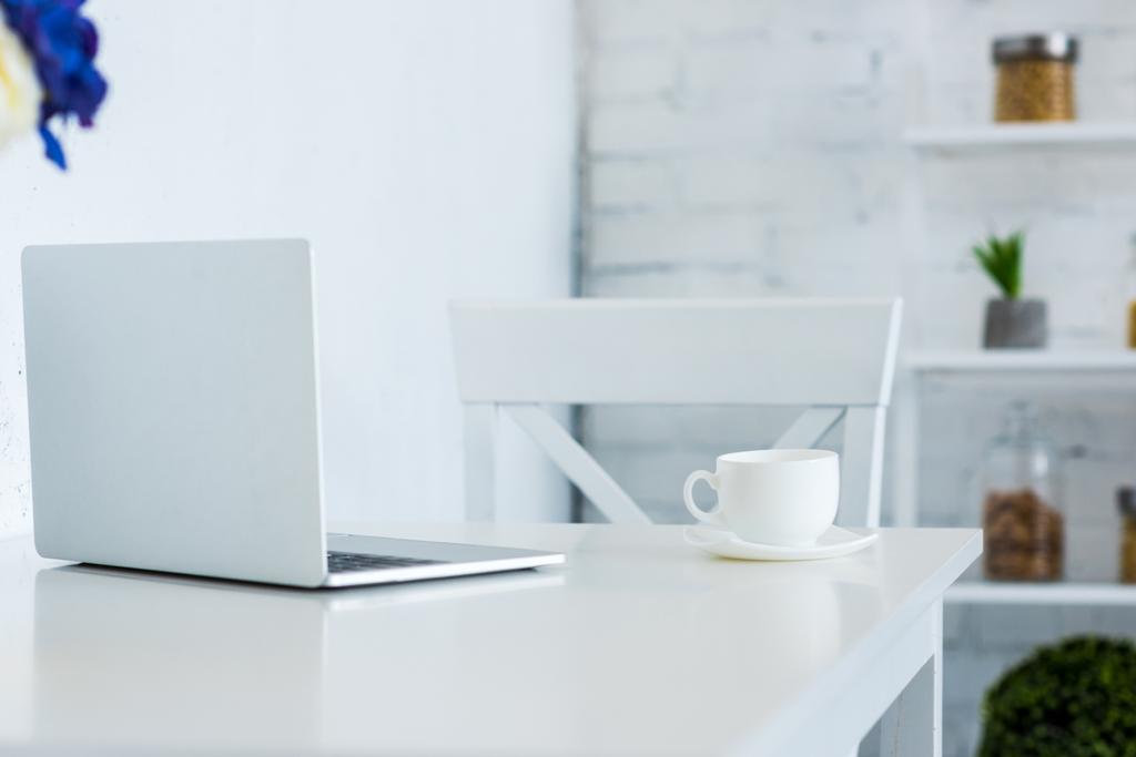 kannettava tietokone ja kuppi kahvia valkoinen pöytä keittiö
 - Valokuva, kuva