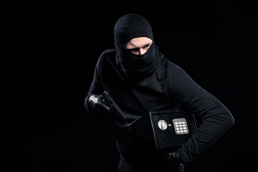 Грабитель в балаклаве держит пистолет и заперт в сейфе
 - Фото, изображение