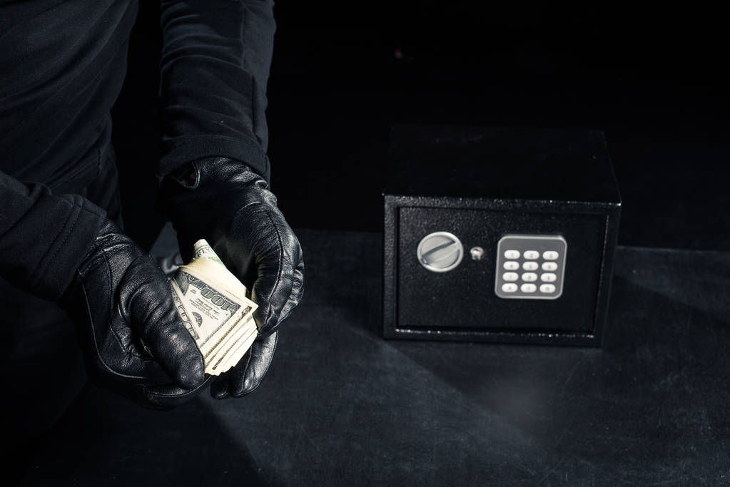 Vista de perto do ladrão em luvas levando dólares do cofre
 - Foto, Imagem