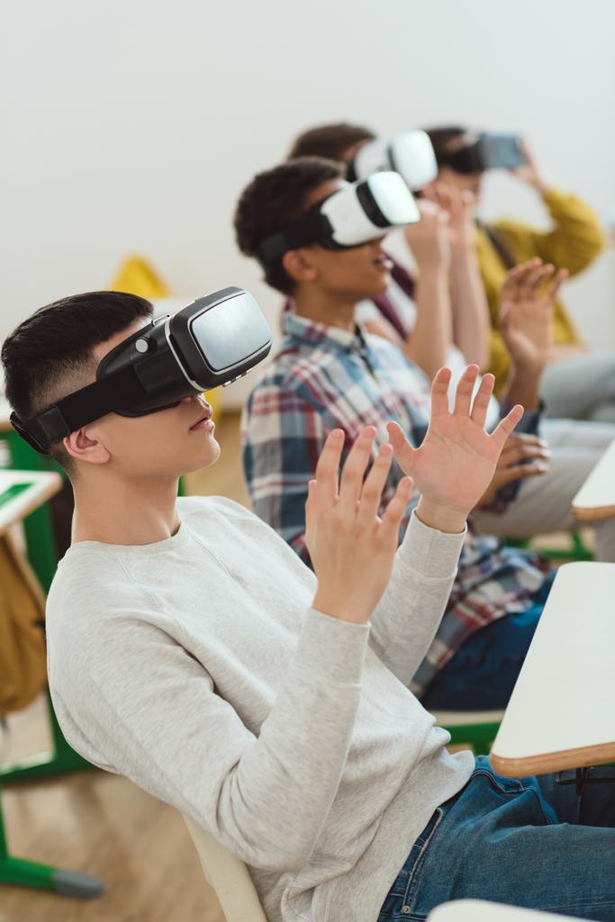 Vista laterale degli scolari multiculturali che utilizzano cuffie di realtà virtuale
  - Foto, immagini