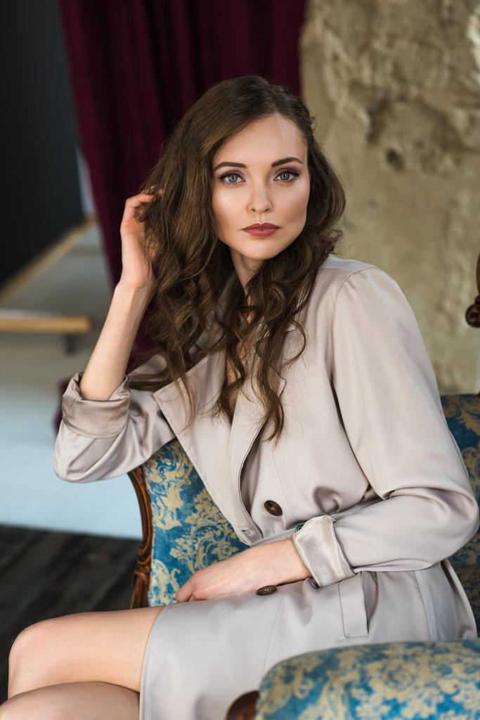 elegant woman in fashionable trench coat sitting in armchair - Photo, Image