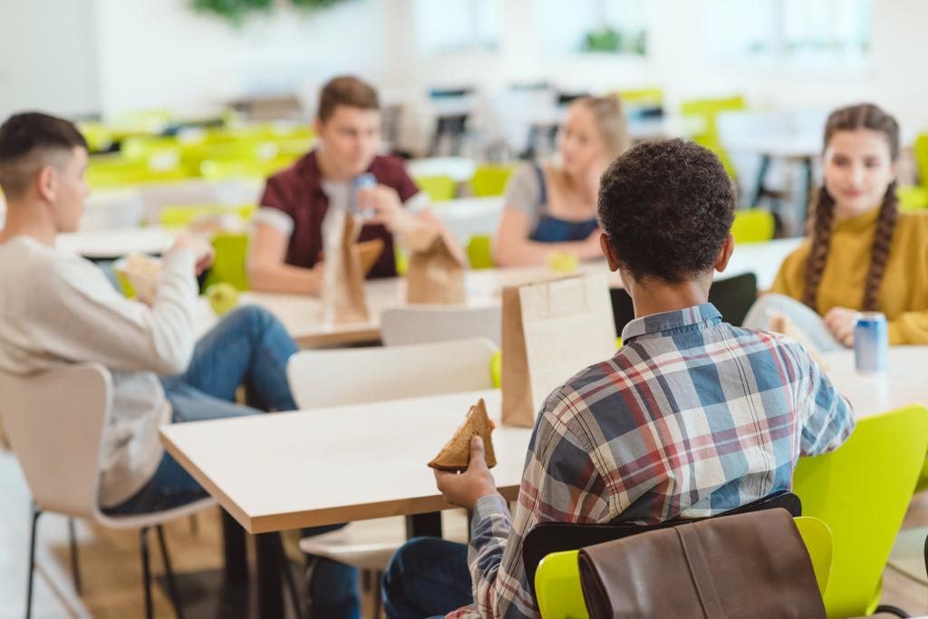 grupo de estudiantes adolescentes charlando mientras almuerzan en la cafetería de la escuela
 - Foto, Imagen