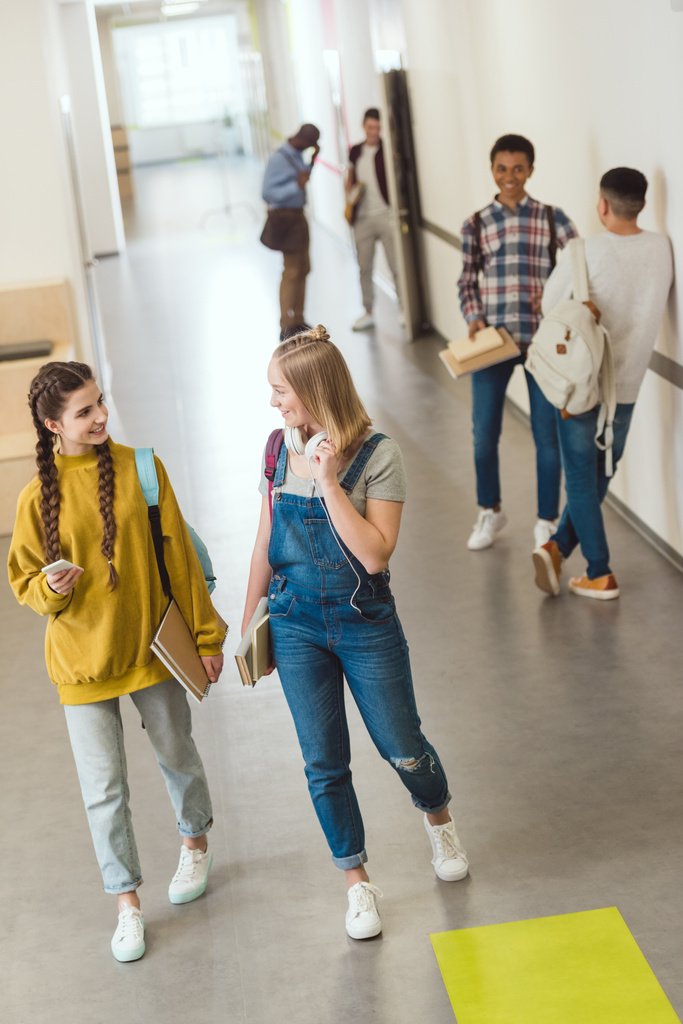 группа мультиэтнических старшеклассников проводит время в школьном коридоре во время перерыва
 - Фото, изображение