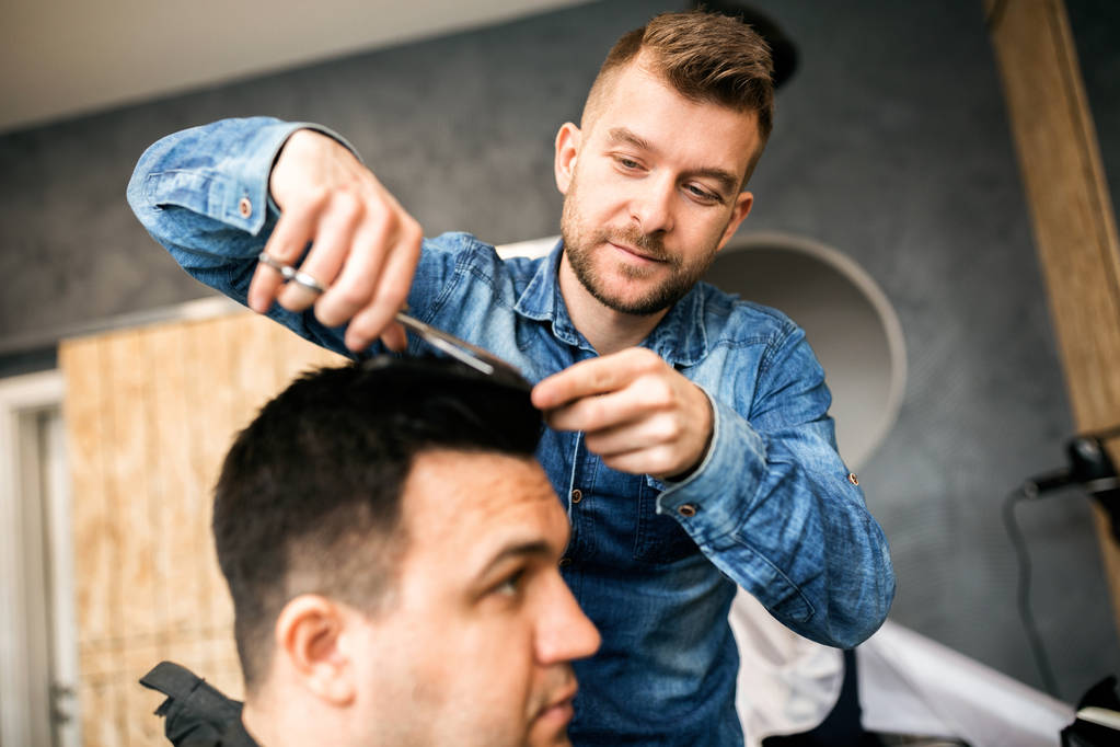 Задоволений чоловік розрізає волосся в перукарні
 - Фото, зображення