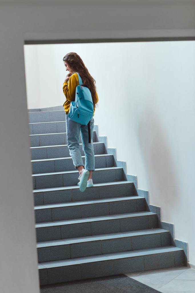 rear view of schoolgirl with backpack walking upstairs - Photo, Image