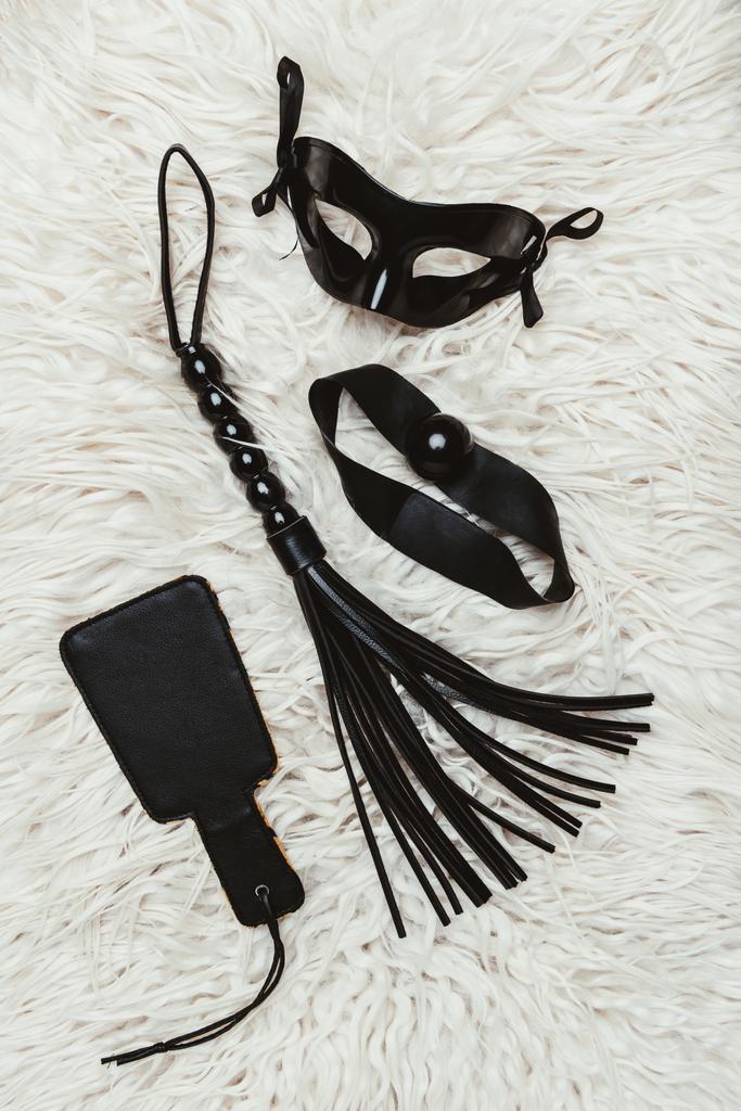 Nalgadas y azotes mordazas con máscara negra en la alfombra blanca
 - Foto, imagen