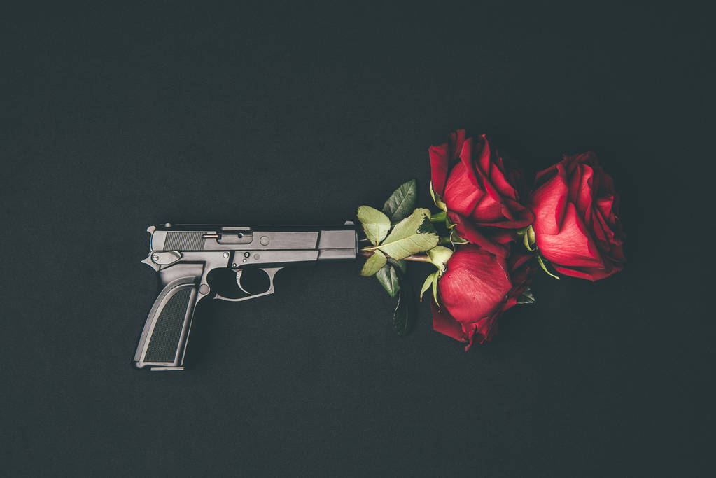 Rosas vermelhas no cano da arma isoladas em preto
 - Foto, Imagem