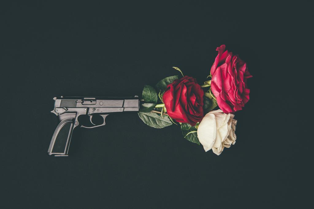 Κάτοψη του όπλου σκοποβολής με τα ροδαλά λουλούδια που απομονώνονται σε μαύρο - Φωτογραφία, εικόνα