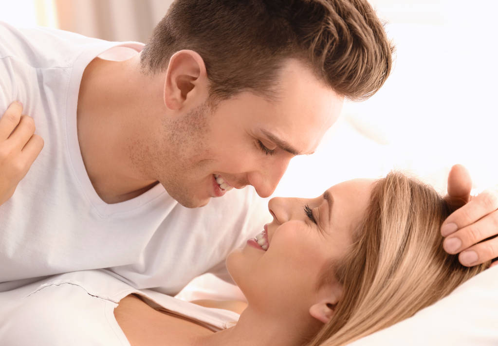 Beautiful young couple being intimate in bed at home - Photo, Image