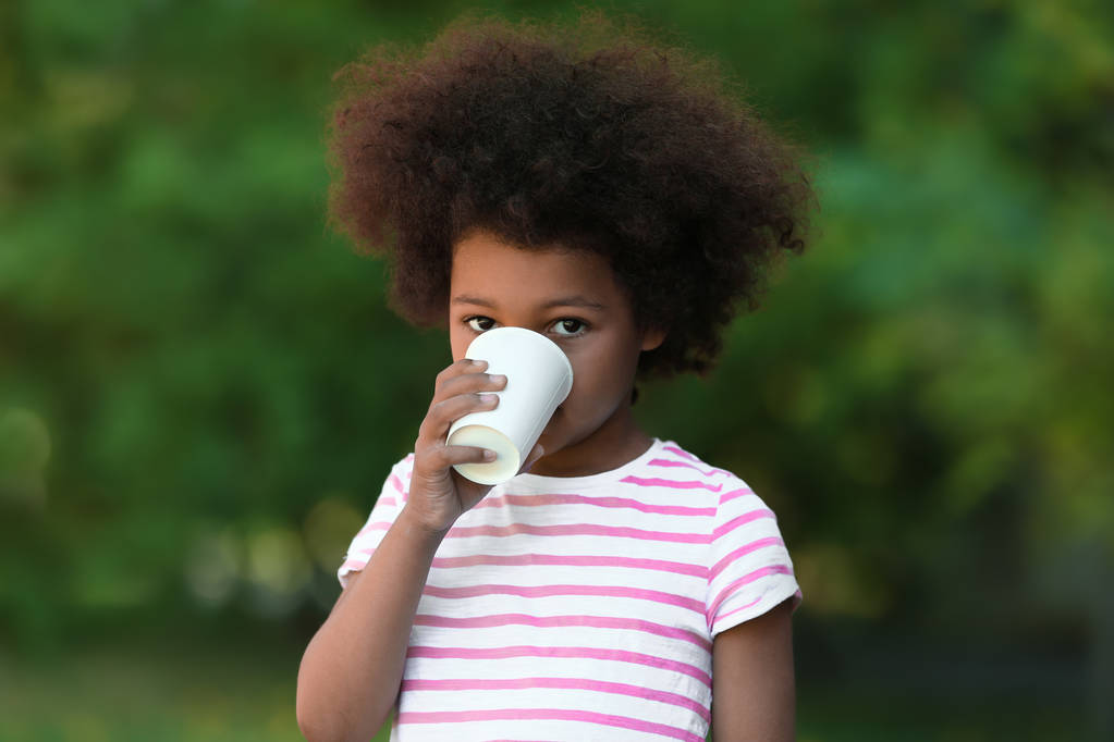 Criança afro-americana a beber água ao ar livre. Conceito de escassez de água
 - Foto, Imagem