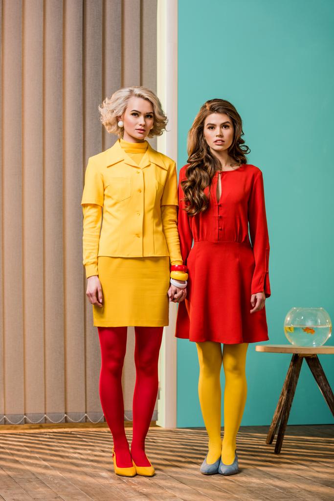 women in bright retro styled clothing holding hands at colorful apartment, doll house concept - Photo, Image