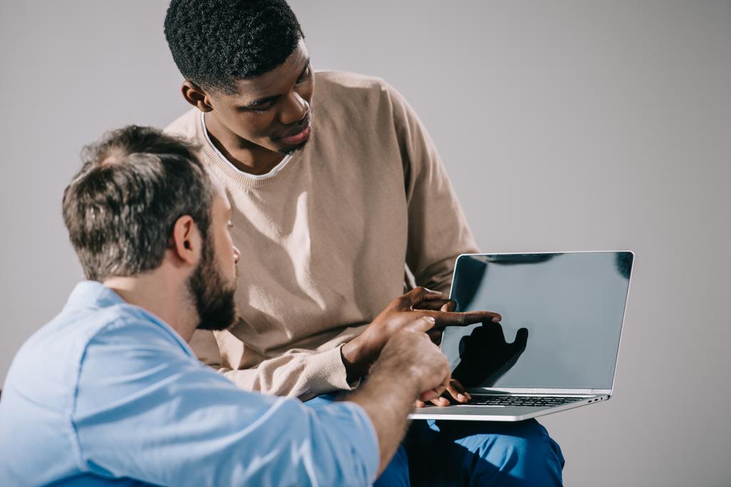 uomini multietnici guardando computer portatile con schermo vuoto
 - Foto, immagini