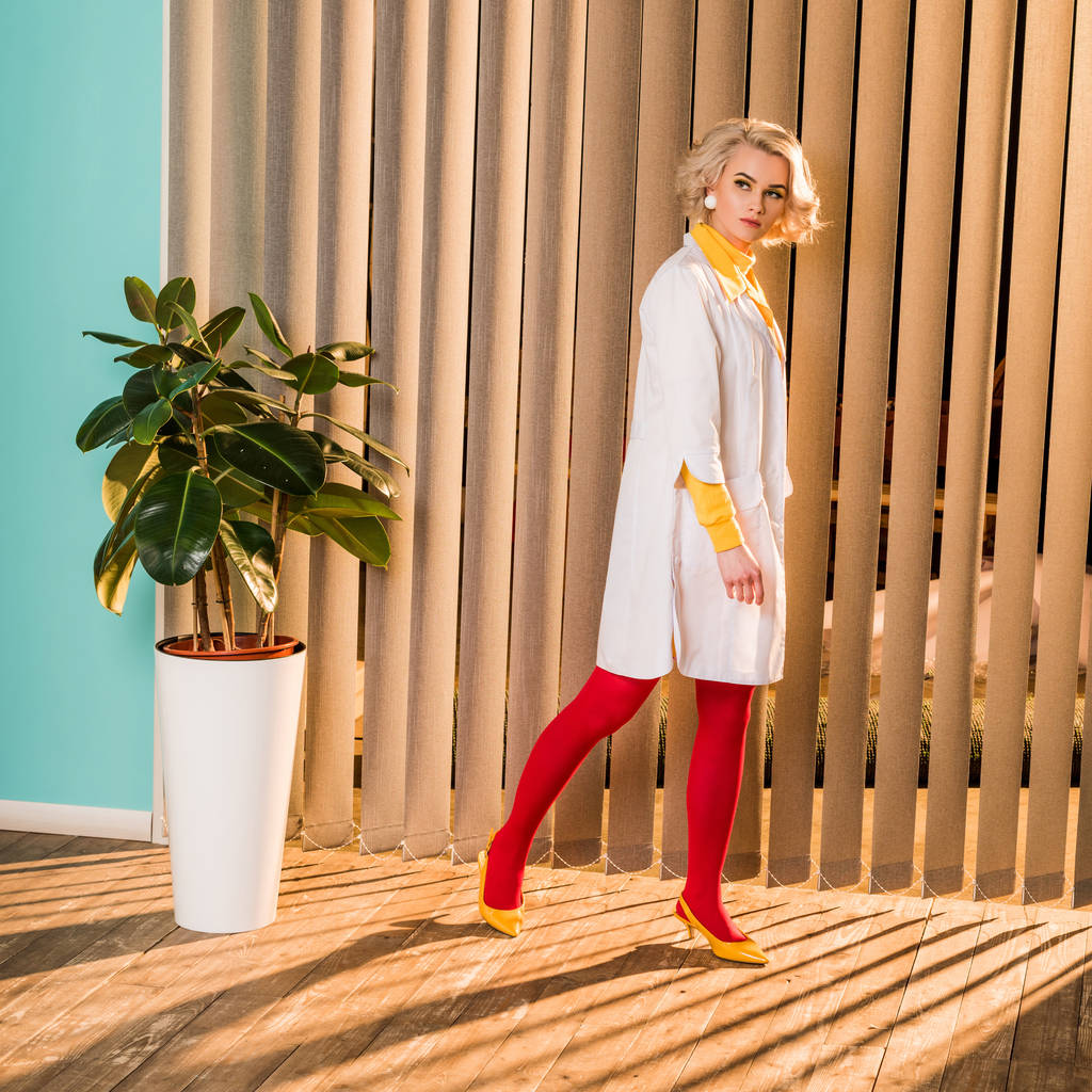 όμορφα ρετρό στυλ γιατρός στο πολύχρωμο φόρεμα και άσπρο παλτό περπάτημα στην κλινική - Φωτογραφία, εικόνα