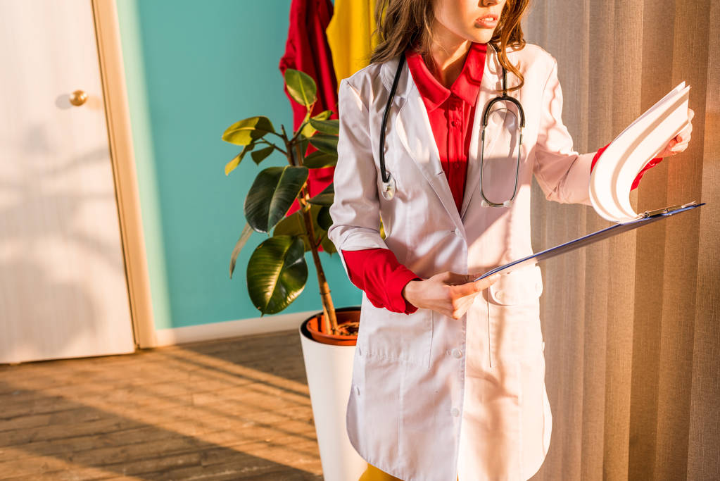 обрезанное изображение врача в стиле ретро, смотрящего в буфер обмена в клинике
 - Фото, изображение