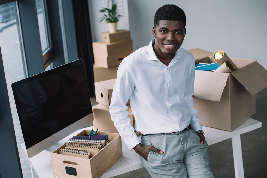 heureux jeune homme d'affaires afro-américain souriant à la caméra tout en déménageant dans un nouveau bureau
 - Photo, image