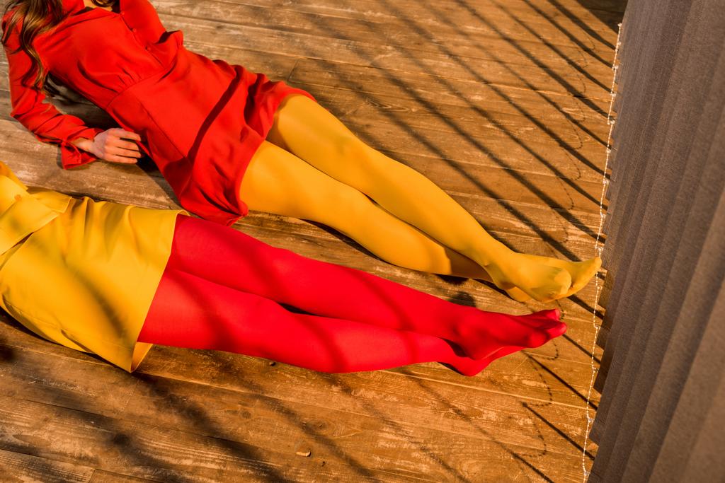 cropped image of girls in colorful tights and dresses lying on floor at home - Photo, Image