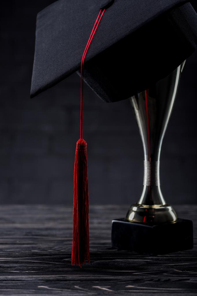 Copo de troféu com copo de graduação na mesa de madeira
 - Foto, Imagem