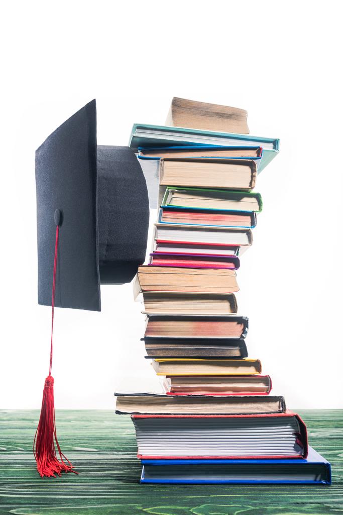 Boné de graduação fixado entre livros empilhados
 - Foto, Imagem