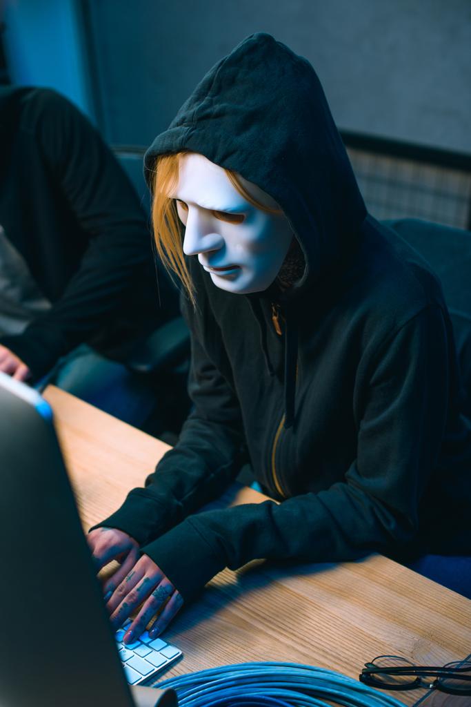 vista de ángulo alto de hacker en la máscara de trabajo con la computadora para desarrollar malware
 - Foto, imagen