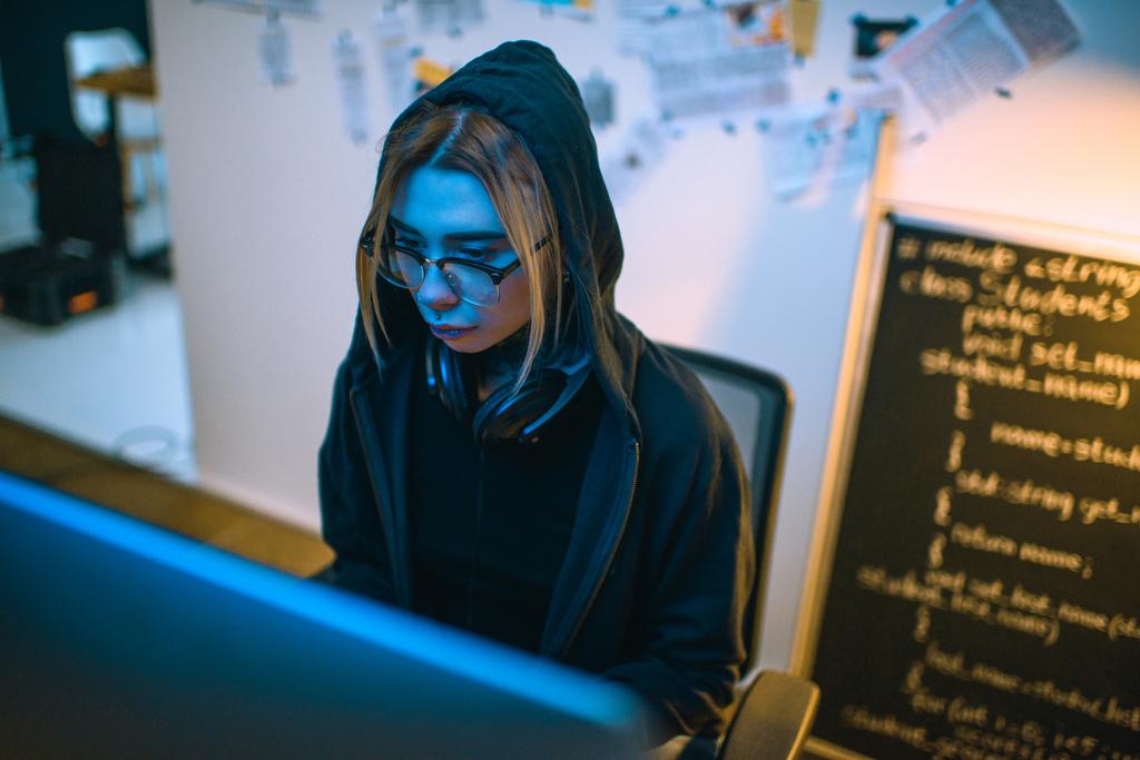 hoge hoekmening van vrouwelijke hacker ontwikkeling van malware onder blauw licht - Foto, afbeelding