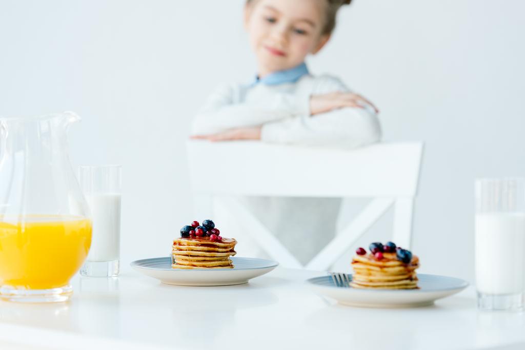 テーブルの上の果実と蜂蜜と自家製のパンケーキを見て子供の選択と集中 - 写真・画像