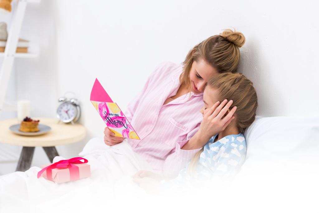matka dcera objímání a drží pohlednice šťastný den matek - Fotografie, Obrázek