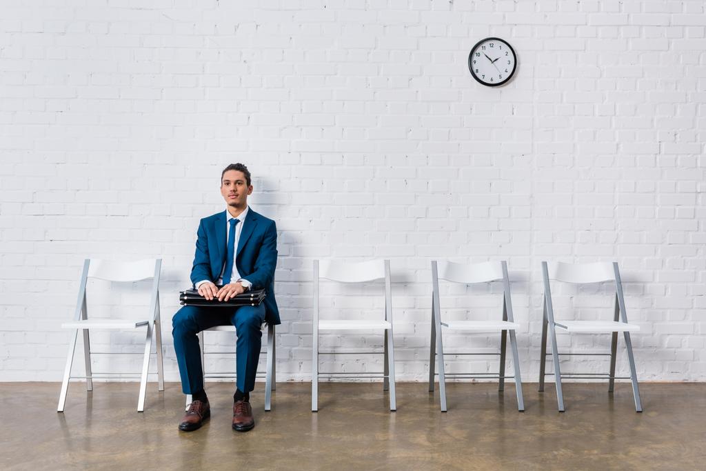 Empresário com pasta sentada na cadeira e esperando
 - Foto, Imagem