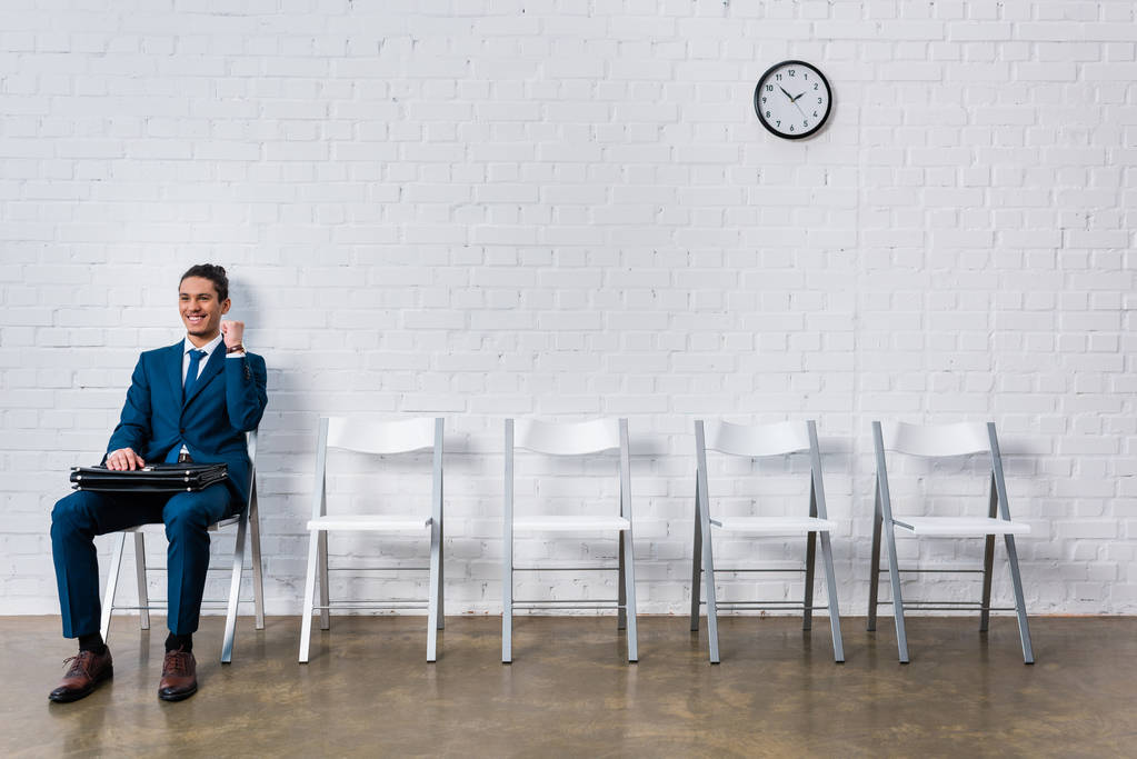 Concept van succesvolle interview met jonge gelukkig zakenman zit op stoel - Foto, afbeelding