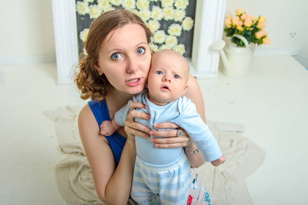 junge blonde Frau mit Baby in einem hellen Raum - Foto, Bild