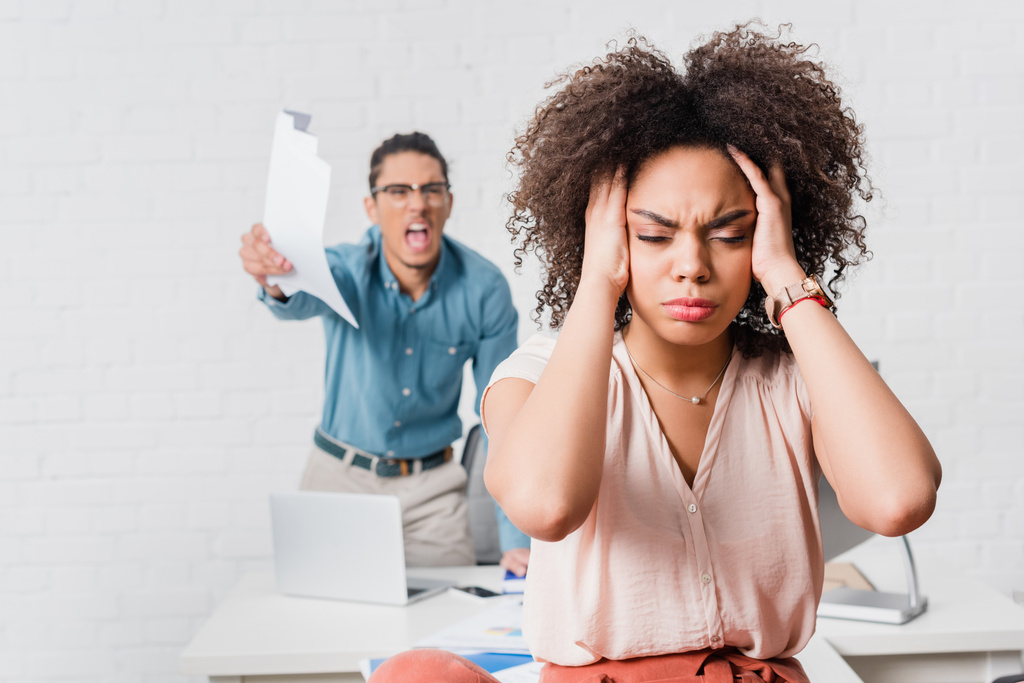 Mujer que sufre de estrés a causa de colega masculino enojado en el cargo
 - Foto, Imagen