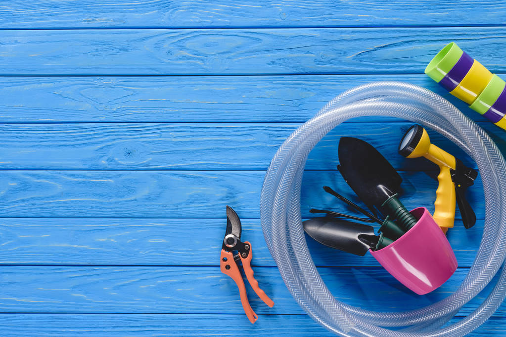 κάτοψη του γλάστρες, Εξάρτυση μάνικας και εργαλεία κηπουρικής στις ξύλινες σανίδες για μπλε - Φωτογραφία, εικόνα