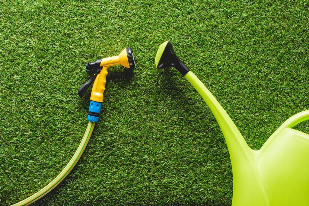 top view of watering can and hosepipe on grass, minimalistic conception - Photo, Image
