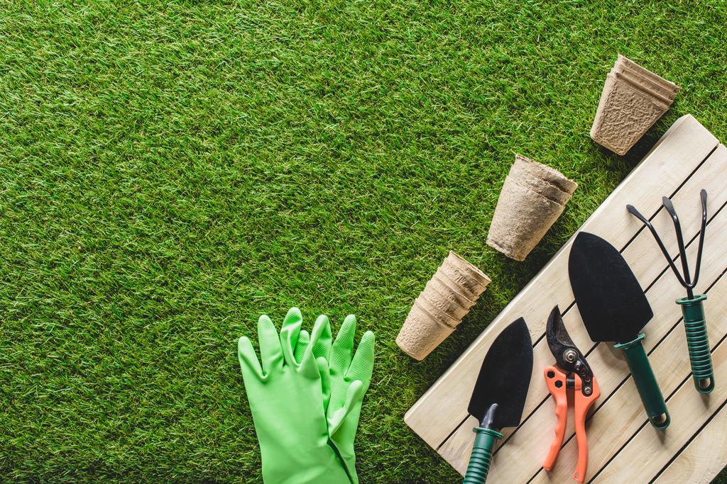 pohled shora ochranné rukavice, květináče a zahradní nářadí na trávě - Fotografie, Obrázek
