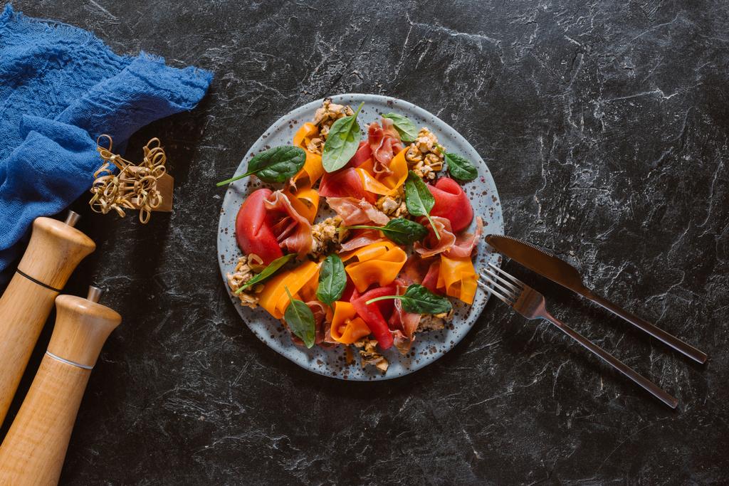 herkullinen salaatti simpukoiden, vihannesten ja jamonin kanssa mustalla marmoripinnalla
 - Valokuva, kuva