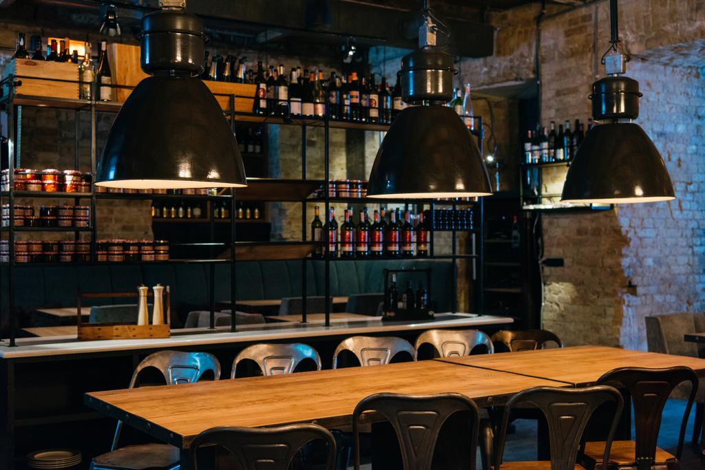 houten tafels, lampen en bar teller in moderne restaurant - Foto, afbeelding