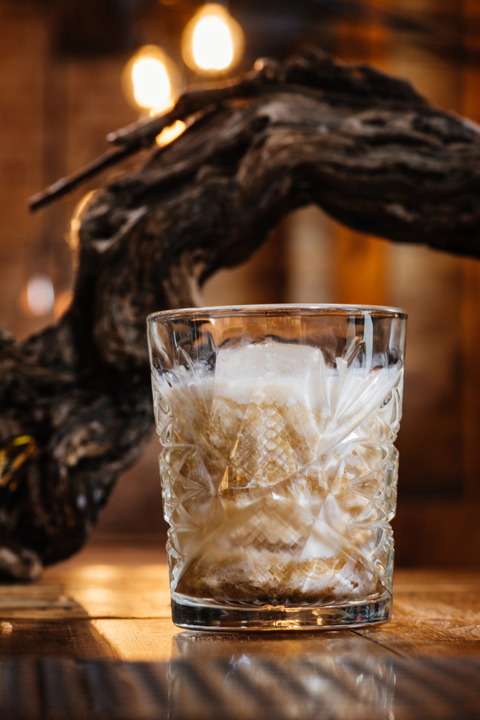 close-up view of alcoholic cocktail with cream in glass on wooden table - Photo, Image