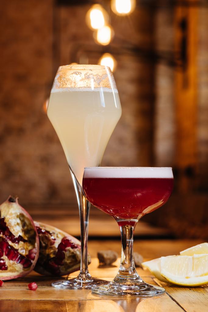 vergrote weergave van bril met alcohol cocktails op houten tafel - Foto, afbeelding