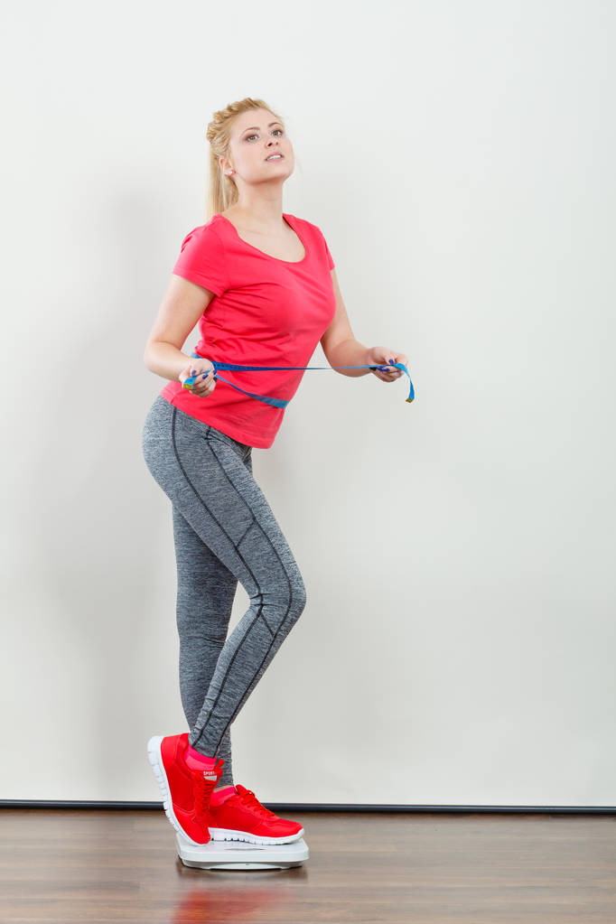 Woman wearing sportswear standing on weight machine - Photo, Image