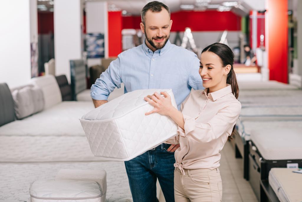 couple choosing folding mattress together in furniture store with arranged mattresses - Photo, Image