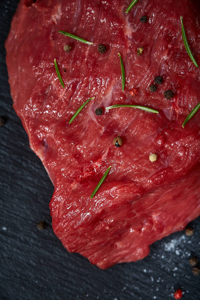 Steki z wołowiny surowego mięsa na czarny Łupek deska z przyprawami i rozmarynem na podłoże drewniane, miejsce - Zdjęcie, obraz