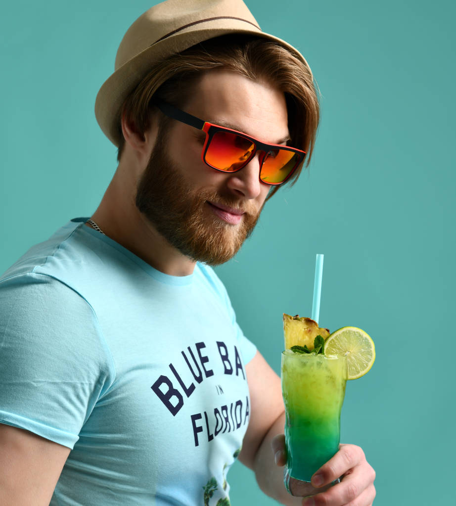 Margarita kokteyl içki suyu kameraya bakarak mutlu içme şapkalı genç adam  - Fotoğraf, Görsel