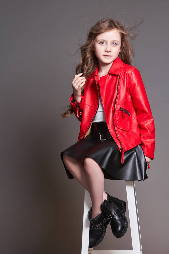 Modekind Mädchen in roter Lederjacke und schwarzem Rock posiert  - Foto, Bild