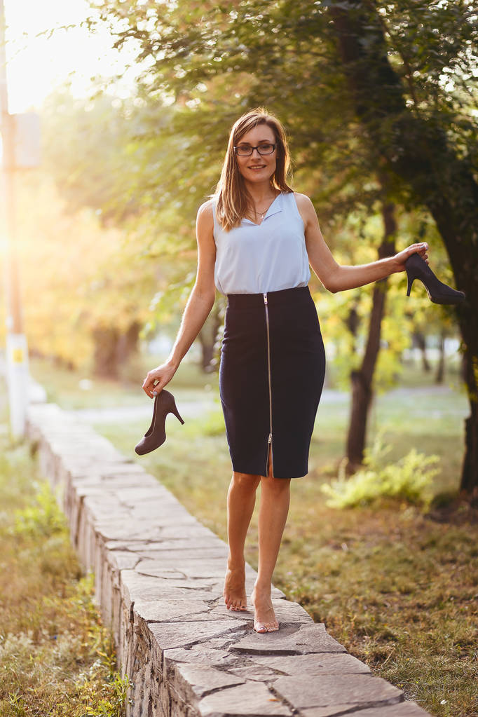 stylish young woman walking barefoot and holding shoes in hand - Photo, Image