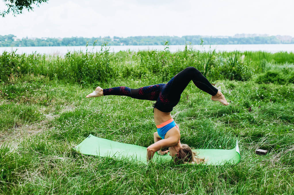 Giovane donna sportiva in abbigliamento sportivo facendo esercizio di yoga all'aperto
 - Foto, immagini